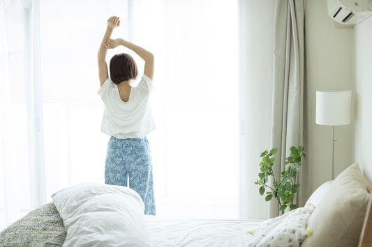 窓際で背伸びをする女性